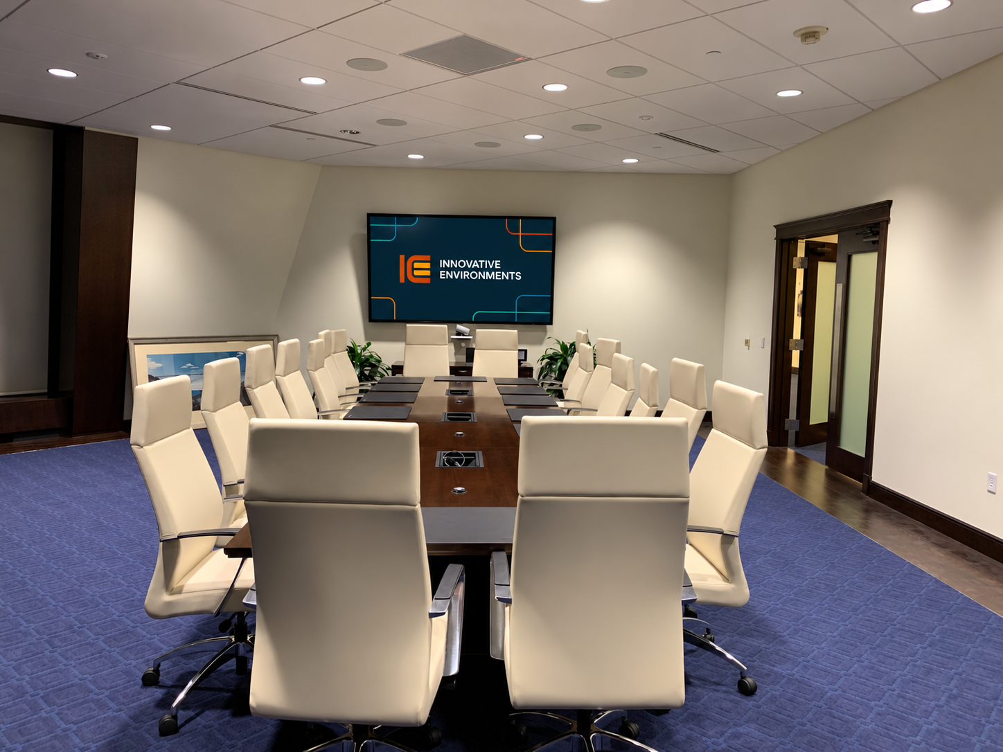 Executive meeting room with a long conference table and wall-mounted display