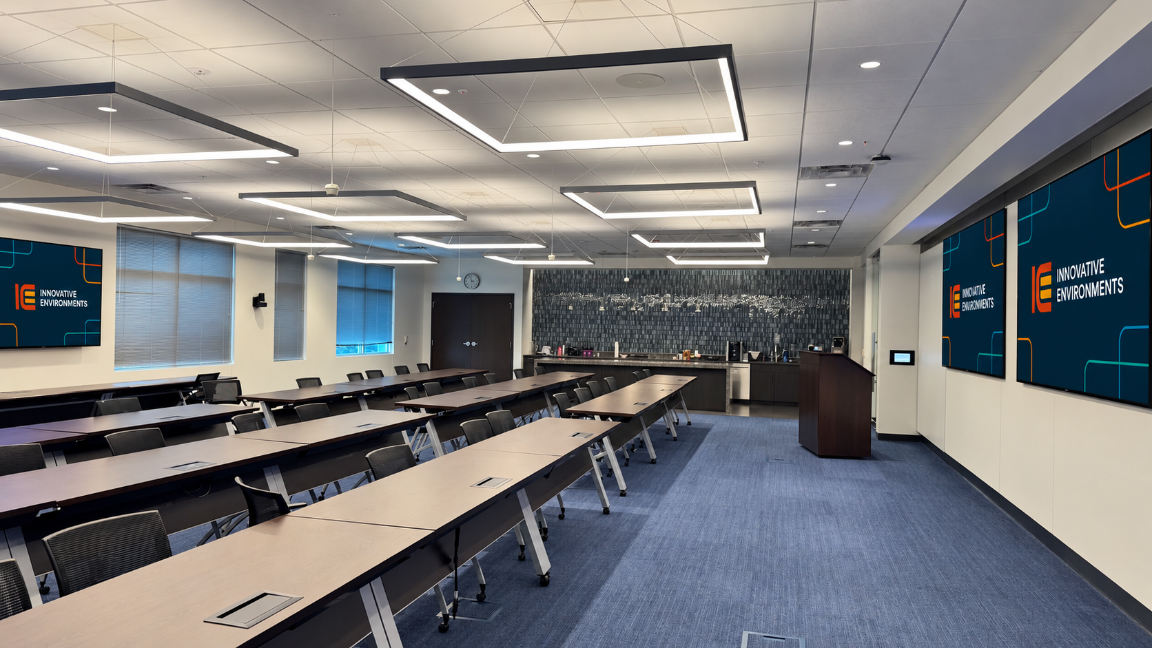 Wide training space with tables, ceiling lights, and presentation displays